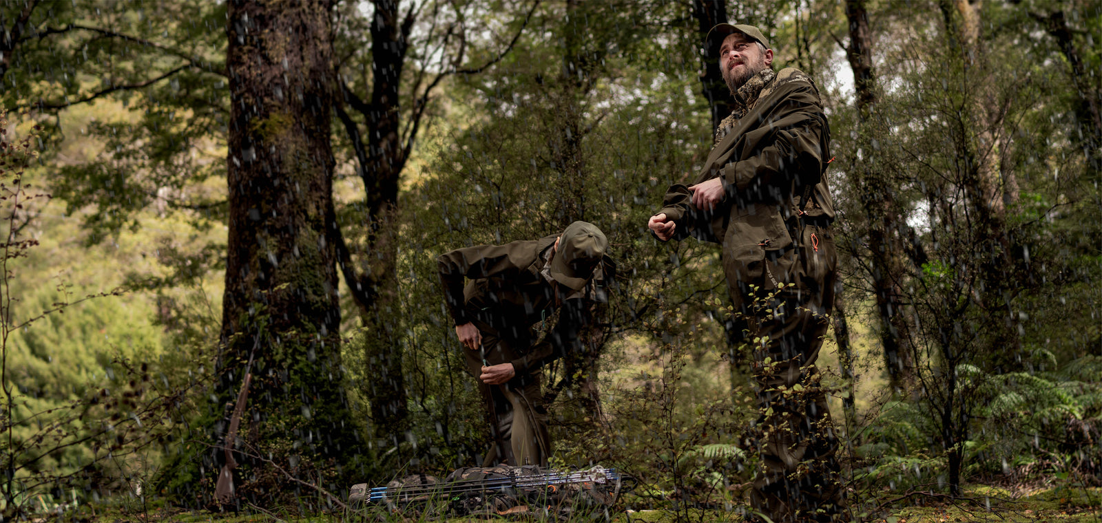 Two people in camouflage gear in a forest setting