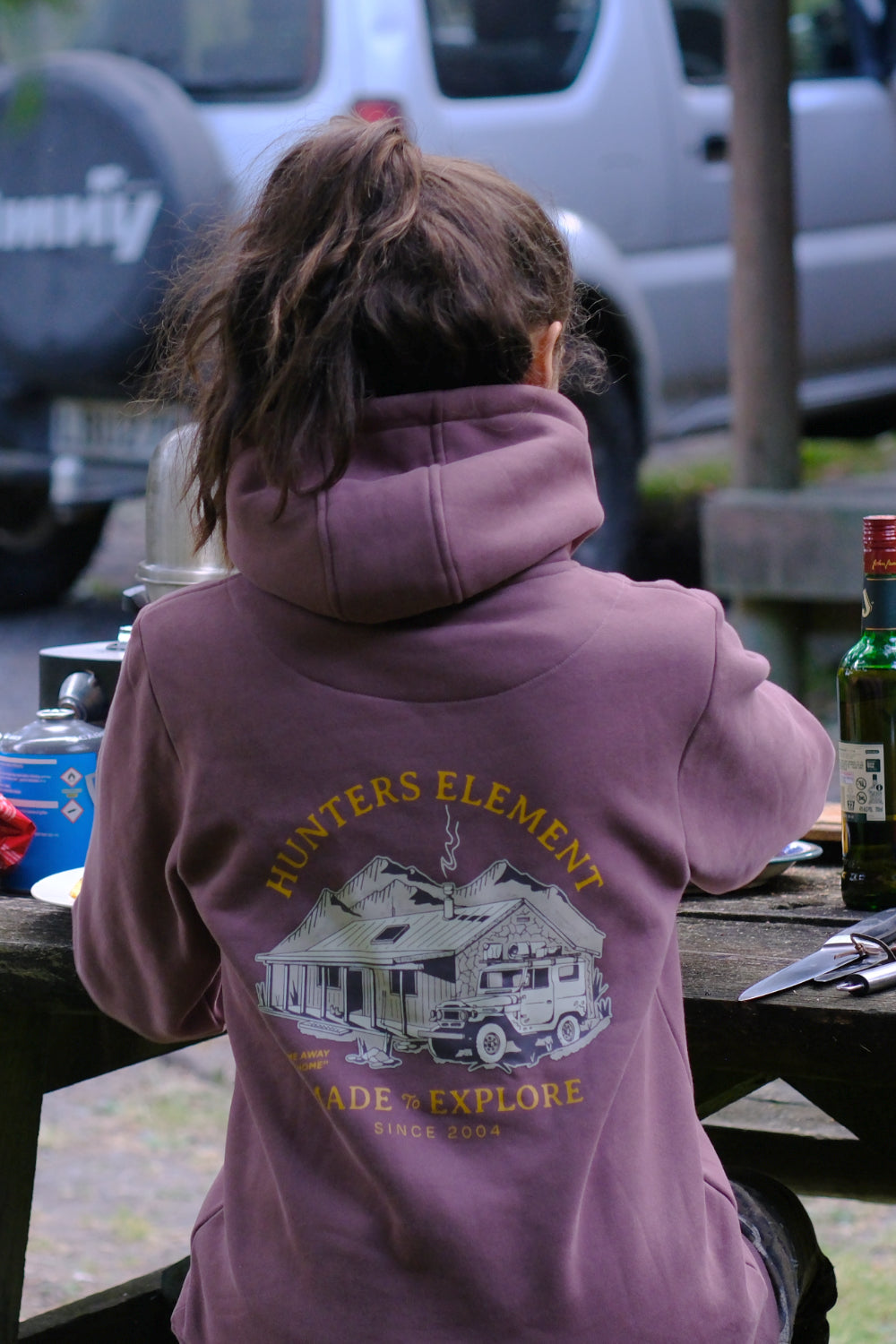Person wearing a purple hoodie with 'Hunters Element' logo at a picnic table.