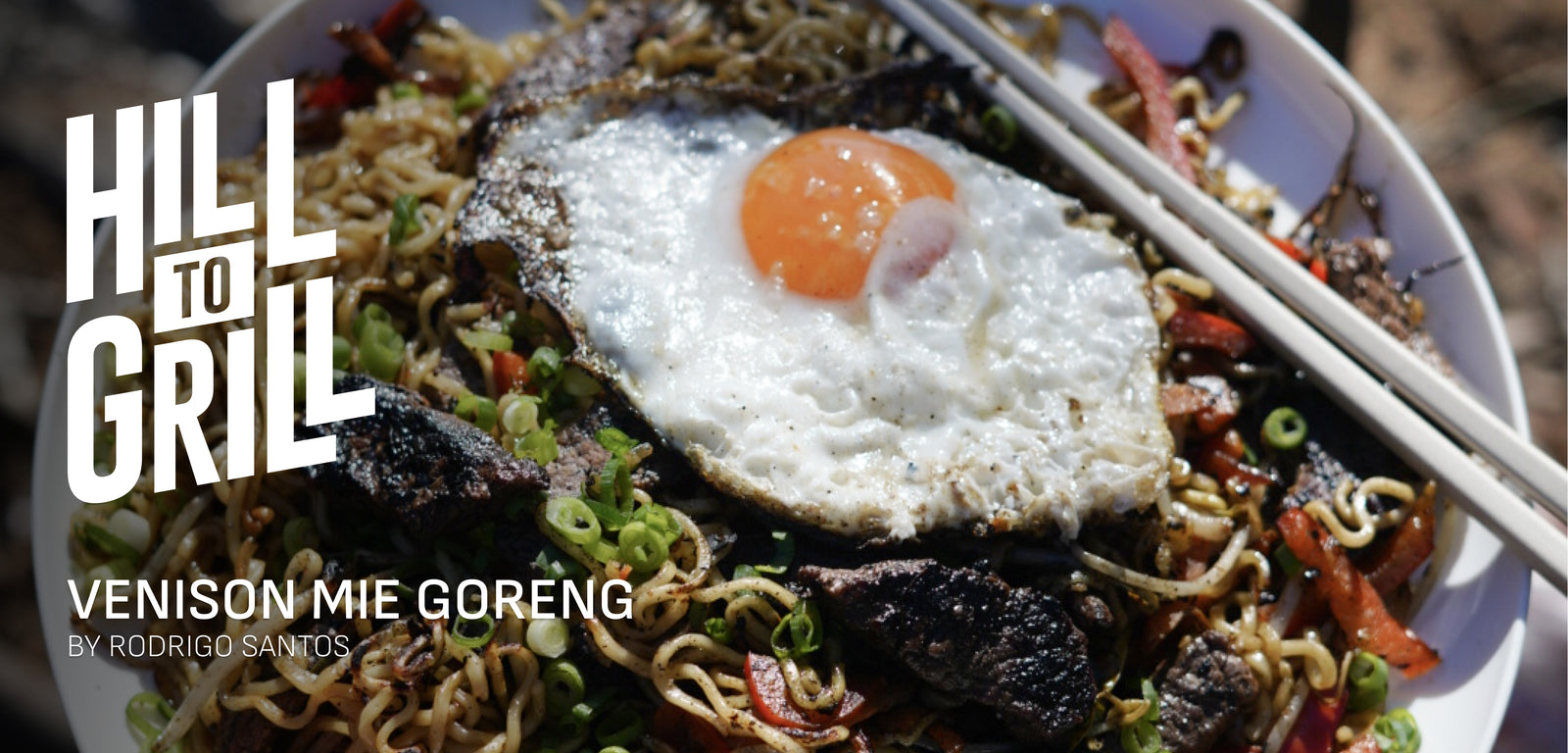 Venison mie goreng with a fried egg on top, served with chopsticks, featuring 'Hill to Grill' branding.