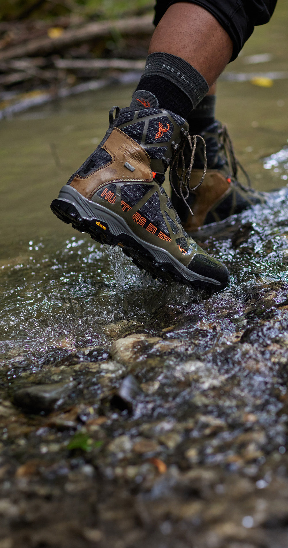 Person wearing brown hiking boots stepping into a stream